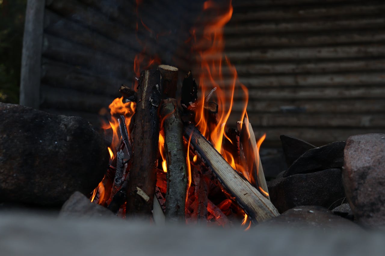 Warm campfire with flames and logs in a rustic outdoor setting, perfect for nature enthusiasts.